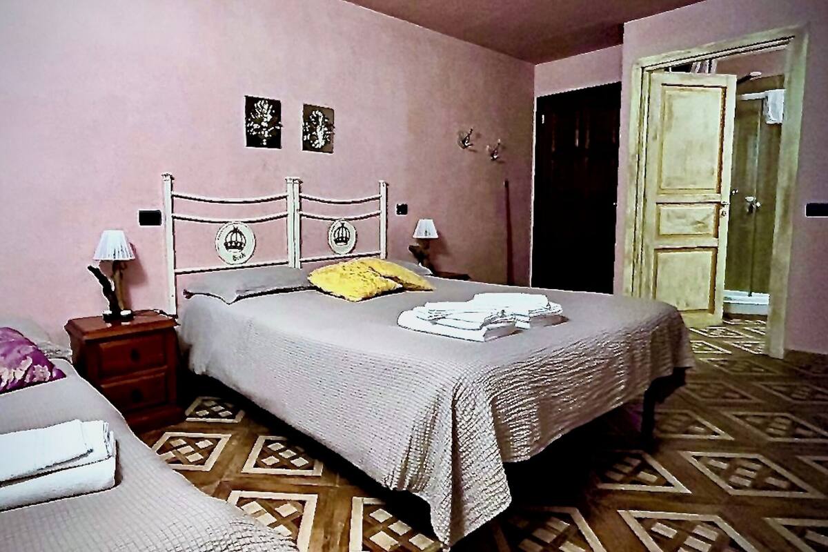 Een slaapkamer met een tweepersoonsbed, een nachtkastje en een deur naar een andere kamer.