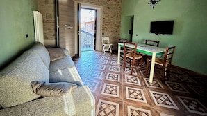 Un salon chaleureux avec un canapé, une table à manger et des chaises, un téléviseur et un sol à motifs.