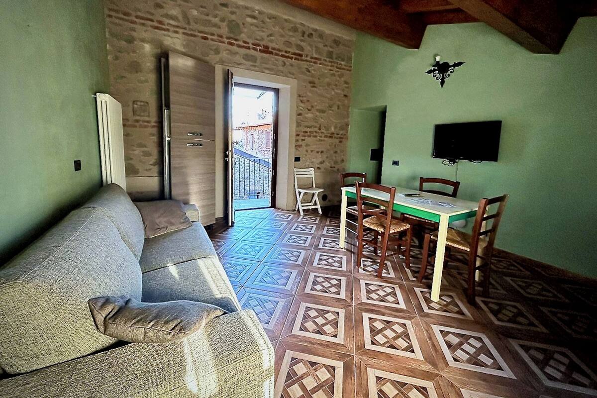 Een gezellige woonkamer met een bank, een eettafel met stoelen, een televisie en een vloer met een patroon.