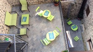 Une terrasse sur le toit, aménagée avec du mobilier d’extérieur de couleur verte, comprenant des chaises et des tables, ainsi que des plantes en pot.