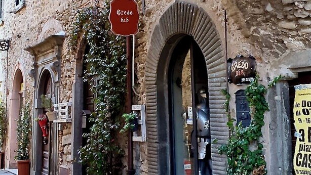 Un bâtiment en pierre doté de fenêtres en arc de cercle et d’une enseigne indiquant « Caffè del Borgo ».