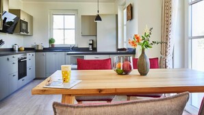 Una cocina moderna con armarios grises, una mesa de comedor de madera y un jarrón con flores.