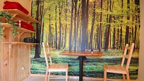 A room with a large forest mural, wooden furniture, and shelves with red towels. - Ferienwohnung am Oase am Vilzsee (Mirow)