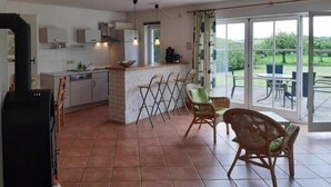Une cuisine spacieuse avec un coin repas, de grandes fenêtres et une vue sur l’extérieur.