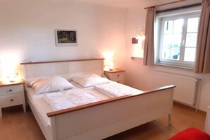 A bedroom with a bed, bedside tables, a window, and a radiator.