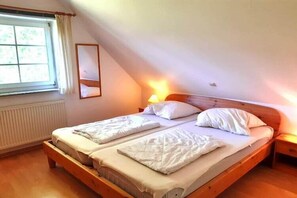 Ein Schlafzimmer mit einem Doppelbett, einem Fenster mit Vorhängen und einem Nachttisch mit Lampe.