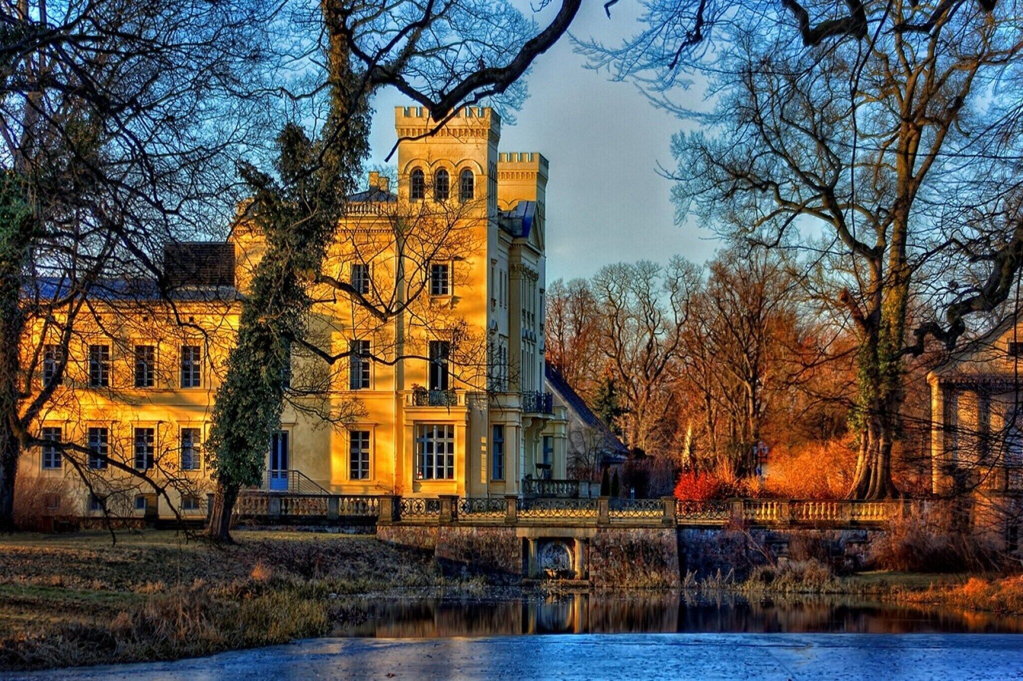 Ein großes, historisches Gebäude mit zahlreichen Fenstern und einem zentralen Turm, umgeben von Bäumen und einem Gewässer.