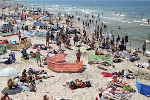 Una platja plena de gent, ombrel·les i cadiretes.