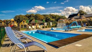 Un espace piscine comprenant des chaises longues et un toboggan aquatique.