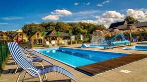Ein Swimmingpool mit Liegestühlen, einer Wasserrutsche und einer strohgedeckten Struktur.