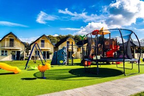 Un parque infantil con diversas estructuras de juego, rodeado de casas.
