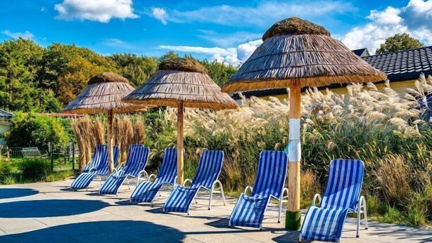 Un espace aménagé au bord de la piscine, avec des chaises longues à rayures et des parasols en chaume.