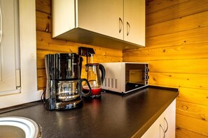 Eine Küchenzeile mit Kaffeemaschine, Wasserkocher und Mikrowelle auf einer Holzauskład.