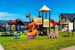 Un parque infantil con tobogán, columpios y una estructura para escalar.