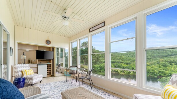 A spacious living area with large windows, a dining table, and a kitchen area. - Lakeview Penthouse Condo with Sunroom & Amenities (Branson)