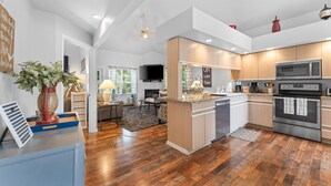 A modern kitchen with wooden cabinets, a built-in microwave, and a large island. - Lakeview Penthouse Condo with Sunroom & Amenities (Branson)