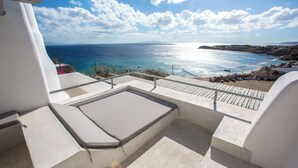 Un balcon avec vue sur la mer, une terrasse en bois et un bâtiment blanc.