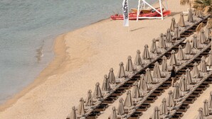 Une tour de surveillance des sauveteurs sur une plage, avec des rangées de chaises longues et de parasols.