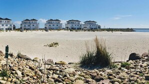 A beachfront property with multiple white buildings, a sandy beach, and a rocky shoreline. - Ferienappartement im Ostseeresort Olpenitz (Ostseeresort Olpenitz)