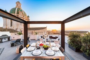 A rooftop dining area with a table set for four, overlooking a cityscape and a historic building with a green dome. - Casa Reina – Trapani Centre (Trapani)