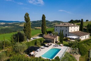 A villa with a swimming pool, outdoor seating, and a view of the surrounding countryside. - Villa La Vigna - Stunning farmhouse with heated private pool (San Casciano dei Bagni)