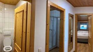 Une pièce avec une porte en bois, une douche et un lit près d’une fenêtre.