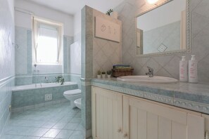 A bathroom with a bathtub, toilet, and sink. There is a mirror above the sink and a window above the bathtub. - Casa Torricelli in zona Crocetta by Wonderful Italy (Turin)