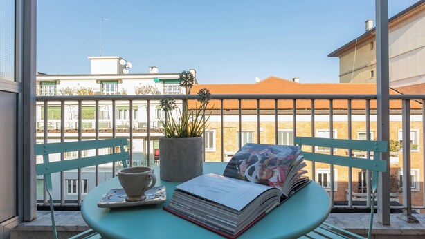 A balcony with a table, a potted plant, and a book. - Casa Torricelli in zona Crocetta by Wonderful Italy (Turin)