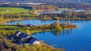 Ein Seeufergrundstück mit einem großen Gebäude, einem Steg und einer kleinen Insel mit Laube.