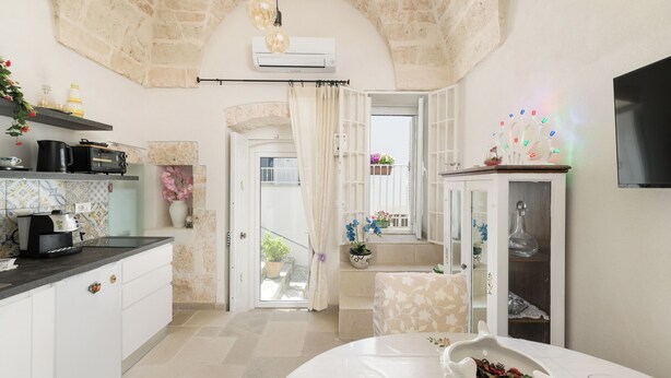 A kitchen with a stone ceiling, a dining area with a table, and a view of the outside. - Stairway with Jacuzzi by Wonderful Italy (Ostuni)