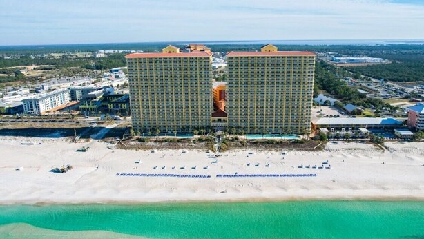 A large hotel with multiple floors and a beach in the foreground.