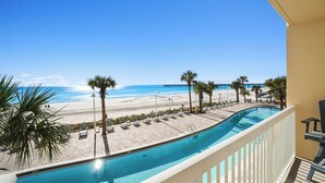 A poolside view with a beach and ocean in the background.