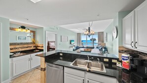 A modern kitchen with a large island, double sinks, and a view to the living area.