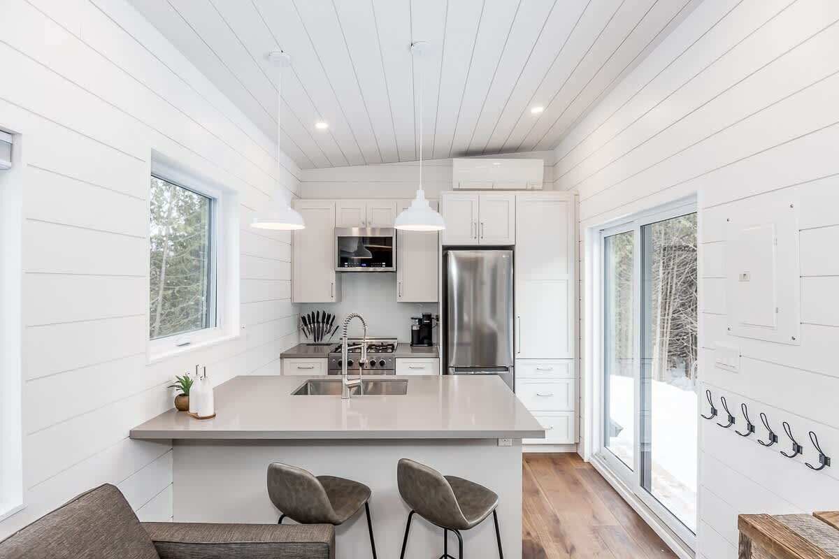 A modern kitchen with white cabinetry, stainless steel appliances, and a central island with bar stools.