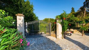 A stone-paved entrance with a metal gate, surrounded by greenery and a motorcycle. - VILLA ALESSANDRA , SANTA AGATA DEI DUE GOLFI (Sant'Agata Sui Due Golfi)