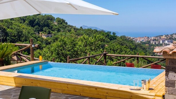A wooden pool with a view of a coastal town and greenery. - VILLA ALESSANDRA , SANTA AGATA DEI DUE GOLFI (Sant'Agata Sui Due Golfi)