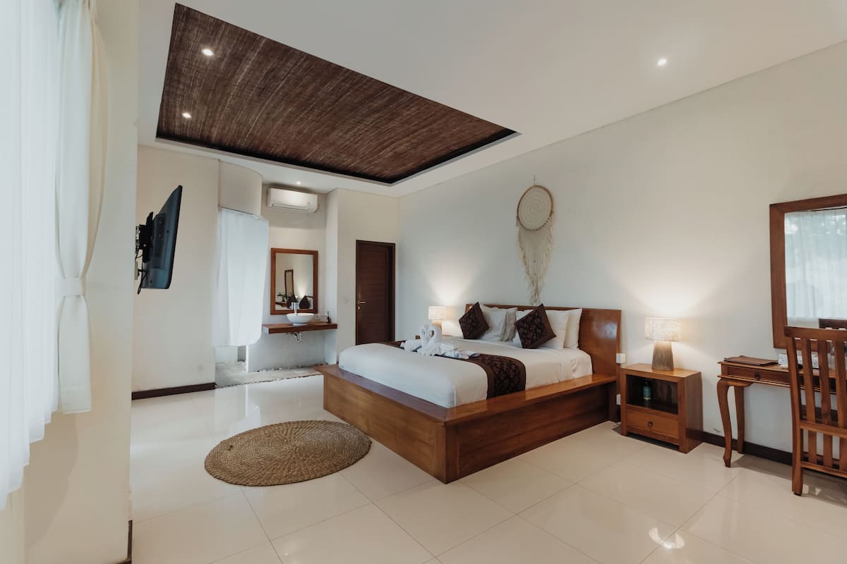 A modern bedroom with a wooden bed, bedside tables, a desk, and a dreamcatcher on the wall.