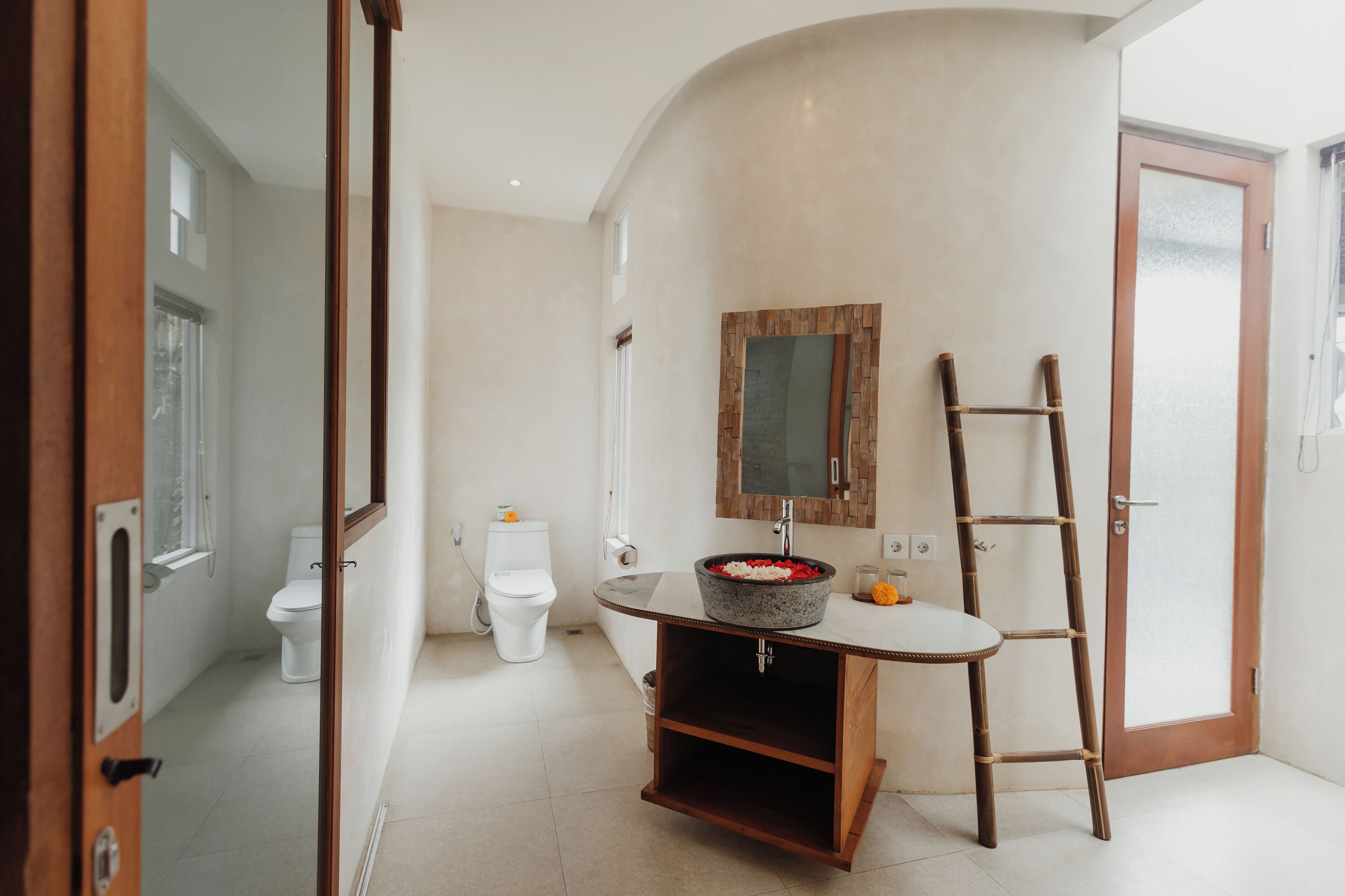 A bathroom with a round sink, a wooden ladder, and a mirror on the wall.