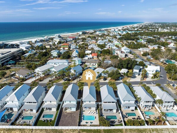 A coastal residential area with houses, a beach, and a clear sky.