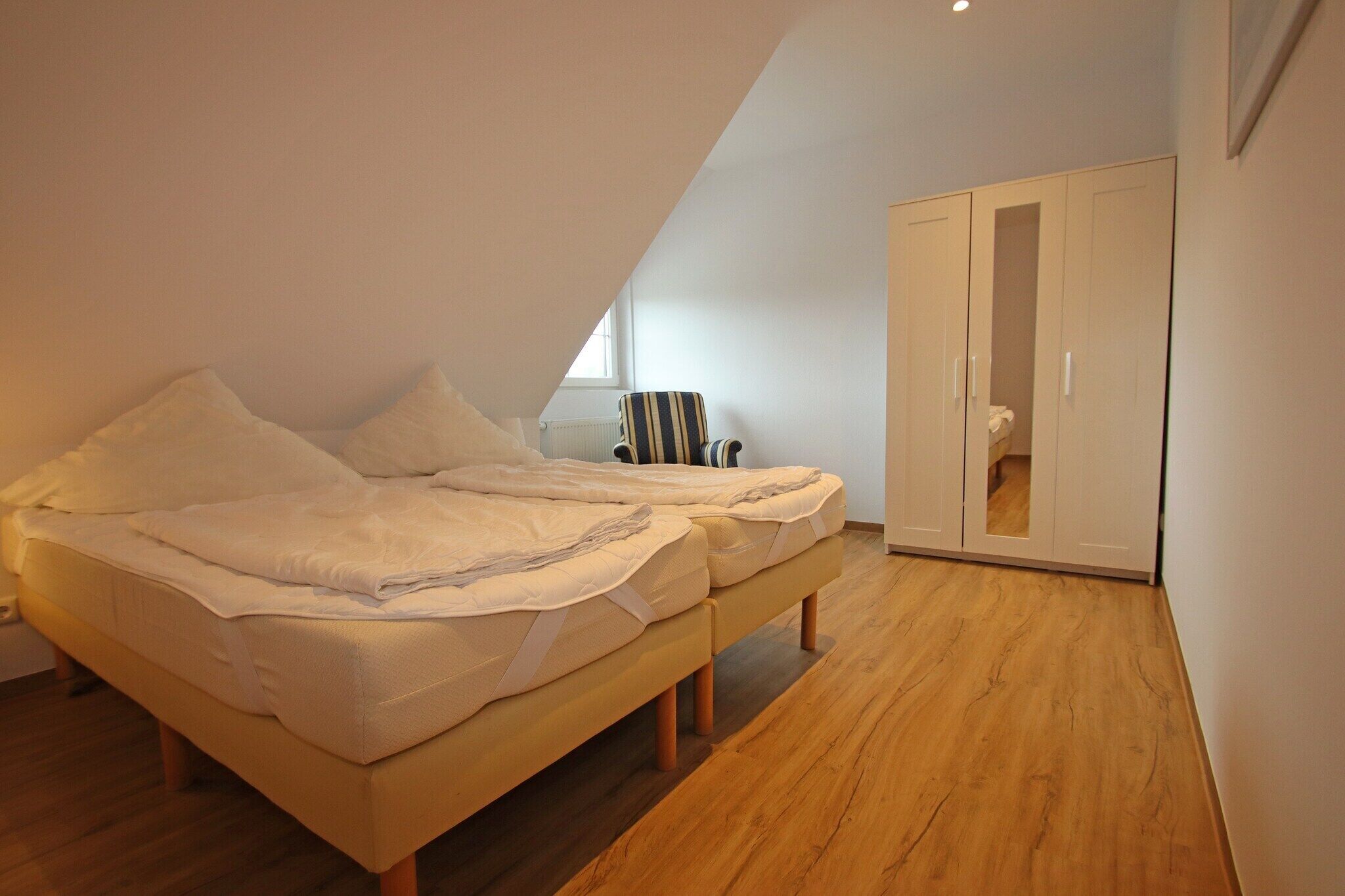 Quarto com cama, cadeira, guarda-roupa e janela.