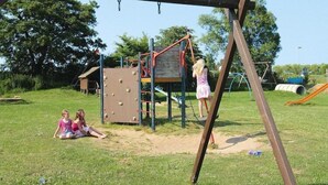 A playground with climbing structures and a swing set in a grassy area.