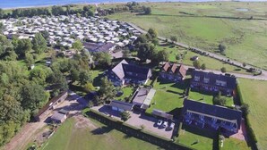 An aerial view of a campground with RVs, a few buildings, and a large open field.