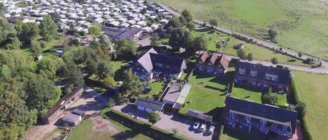 Eine Luftaufnahme eines Campingplatzes mit Wohnmobilen, einigen Gebäuden und einem großen, offenen Feld.