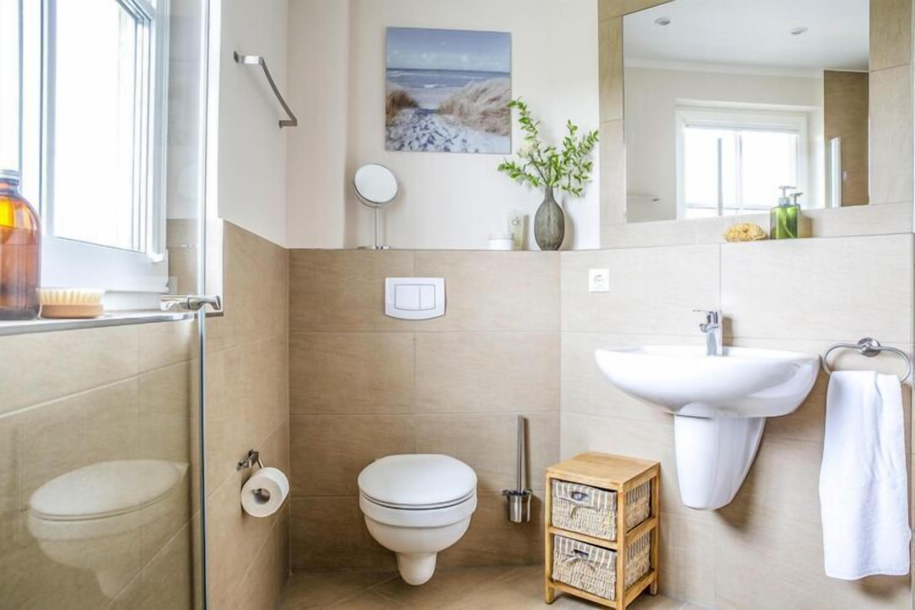 Un bagno con il water, bidet, lavandino e un piccolo mobiletto in legno.