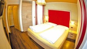 Een hotelkamer met een bed, een kledingkast, een spiegel en een hanglamp.