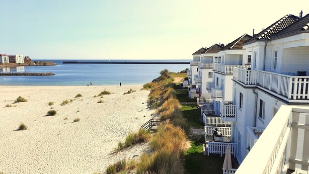 Et strandhotel med en sandstrand, en mole og et klart havudsigt.