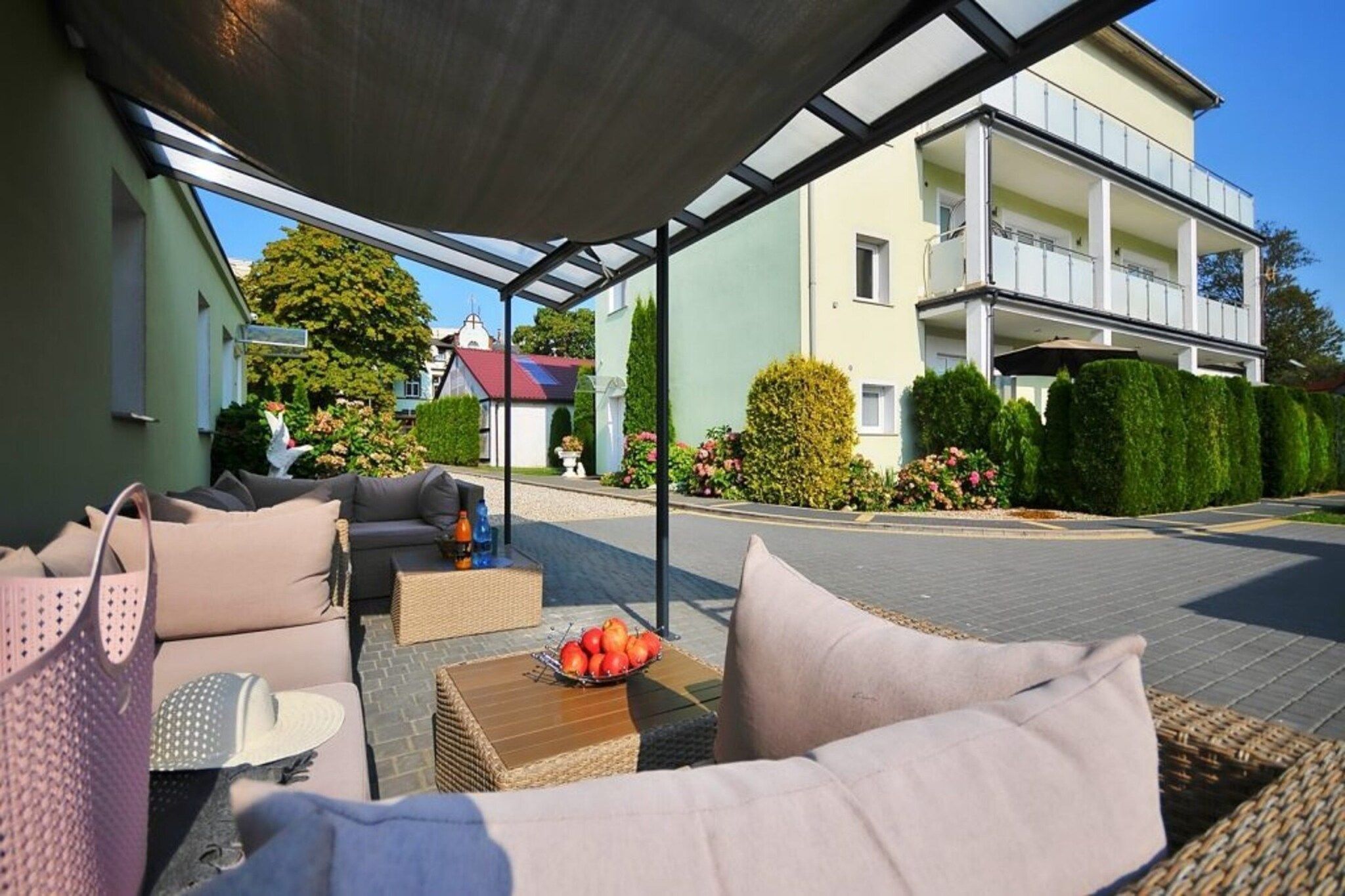 Un espace extérieur aménagé avec un patio couvert, des meubles en osier et un panier de fruits.