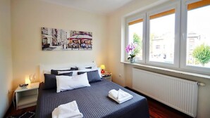 Een hotelkamer met een groot bed, een nachtkastje, een raam met uitzicht op de straat en een schilderij aan de muur.