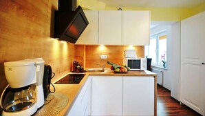 A compact kitchen with white cabinets, a microwave, a coffee maker, and a sink.