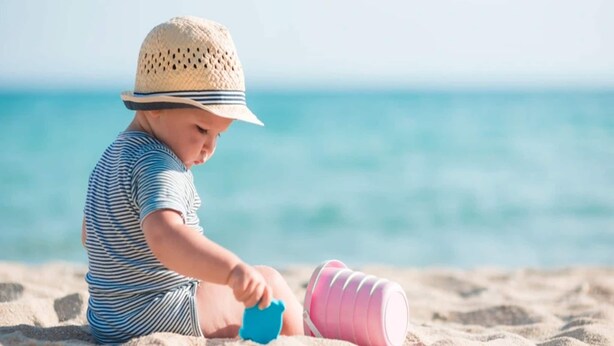 A child playing with sand toys on a beach.